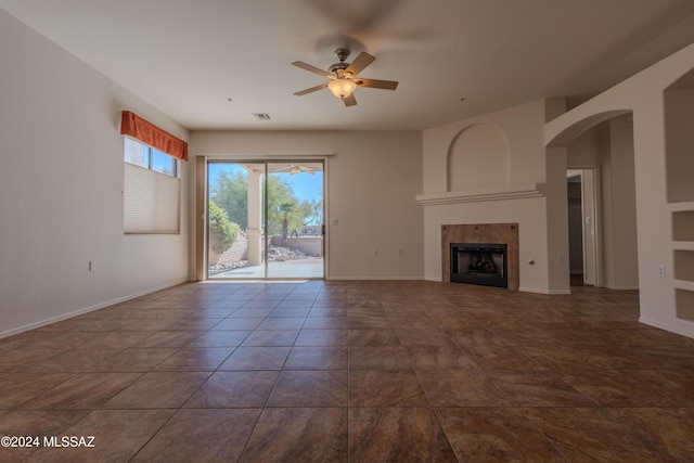 unfurnished living room featuring a tile fireplace and ceiling fan