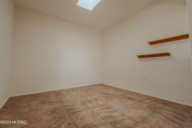 spare room featuring vaulted ceiling with skylight