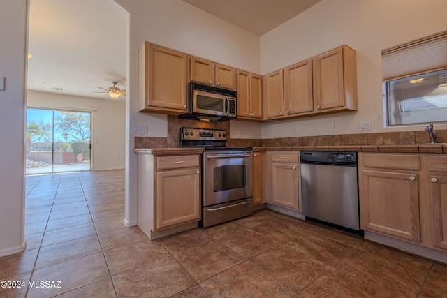 kitchen featuring ceiling fan, appliances with stainless steel finishes, light brown cabinetry, and sink