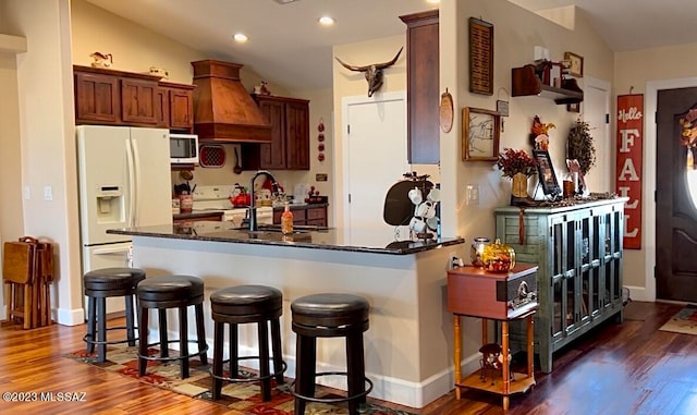 kitchen with custom exhaust hood, sink, kitchen peninsula, white appliances, and dark hardwood / wood-style floors