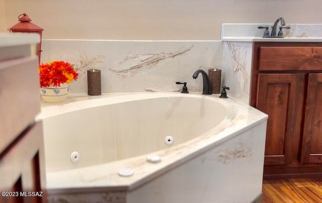 bathroom featuring a bath, hardwood / wood-style floors, and sink