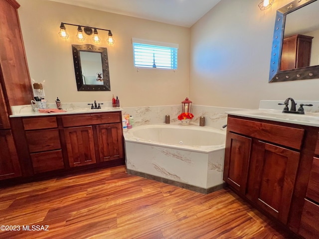 bathroom with wood-type flooring, vanity, vaulted ceiling, and a washtub