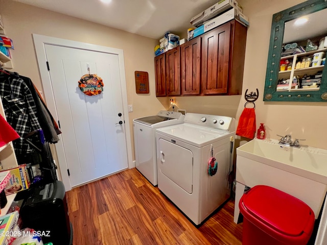 washroom with separate washer and dryer, cabinets, and light hardwood / wood-style flooring