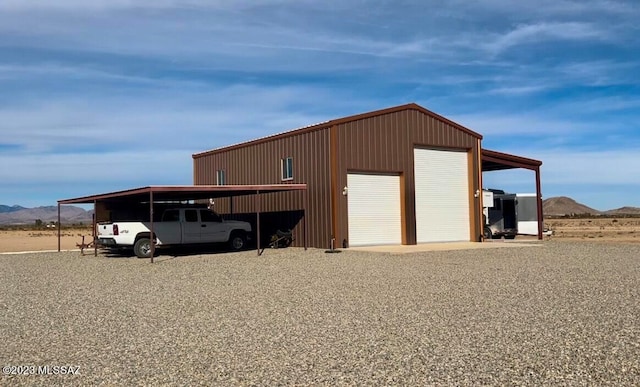 view of outdoor structure with a mountain view, a garage, and a carport