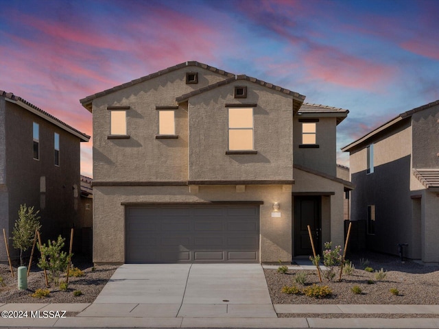 view of front of home featuring stucco siding, driveway, a tile roof, and a garage