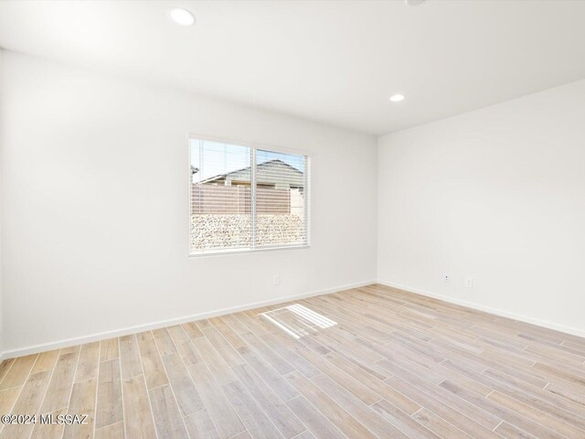 empty room with recessed lighting, light wood-style flooring, and baseboards