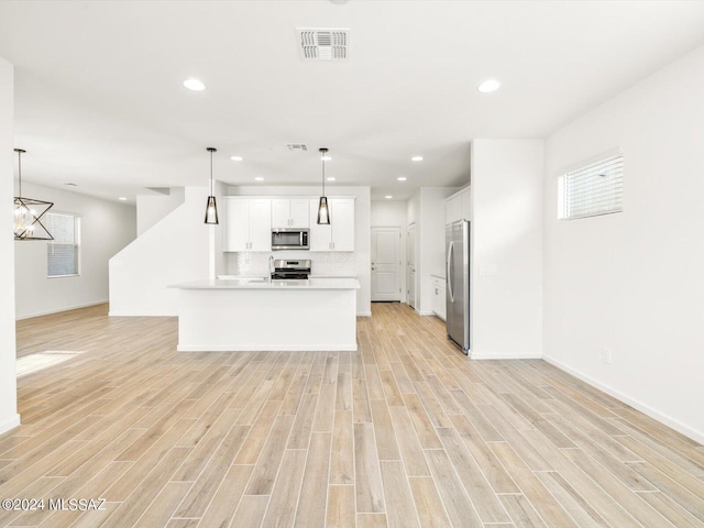 kitchen with visible vents, open floor plan, white cabinetry, light wood-style floors, and appliances with stainless steel finishes