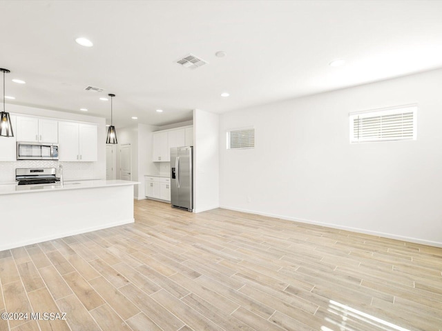 kitchen with tasteful backsplash, visible vents, light countertops, light wood-style flooring, and stainless steel appliances