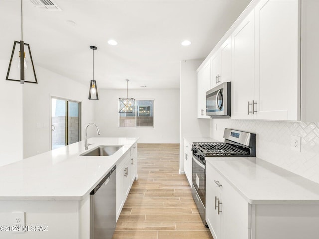 kitchen with tasteful backsplash, visible vents, wood tiled floor, stainless steel appliances, and a sink