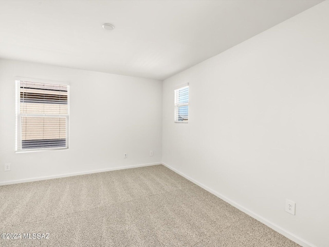 carpeted spare room featuring baseboards