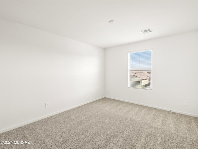 carpeted spare room with visible vents and baseboards