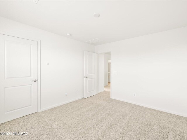 unfurnished room featuring light colored carpet and baseboards