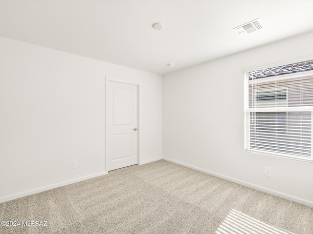 carpeted empty room featuring baseboards and visible vents