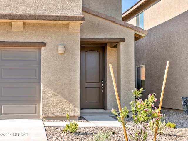 property entrance with stucco siding and a garage