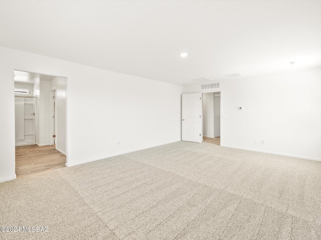 empty room with recessed lighting, light colored carpet, visible vents, and baseboards