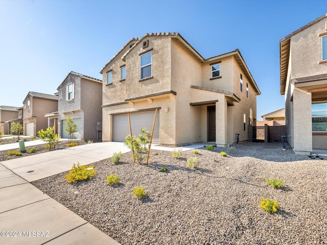 view of front facade featuring stucco siding, driveway, an attached garage, and fence