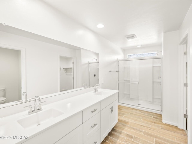 bathroom with double vanity, wood finish floors, toilet, and a sink