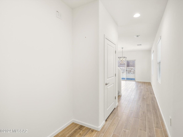 corridor featuring light wood-style flooring, recessed lighting, visible vents, and baseboards