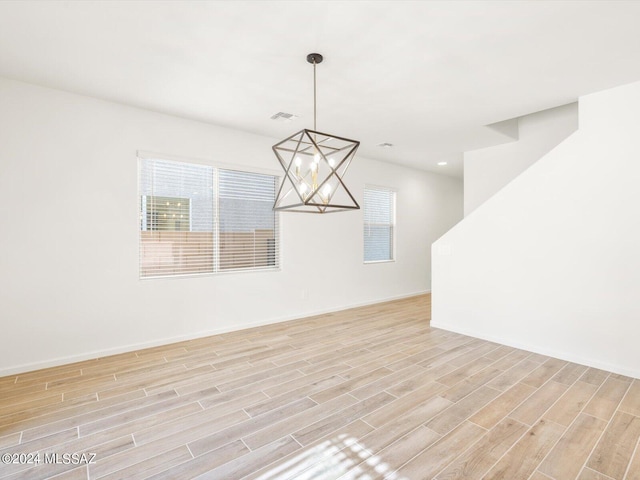 unfurnished room featuring baseboards, visible vents, wood tiled floor, recessed lighting, and a notable chandelier