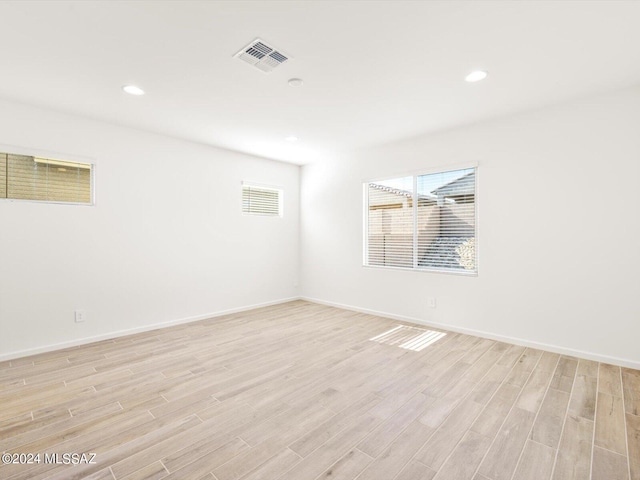 unfurnished room featuring light wood-type flooring, visible vents, baseboards, and recessed lighting