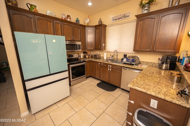 kitchen with sink, appliances with stainless steel finishes, light stone counters, and light tile patterned floors