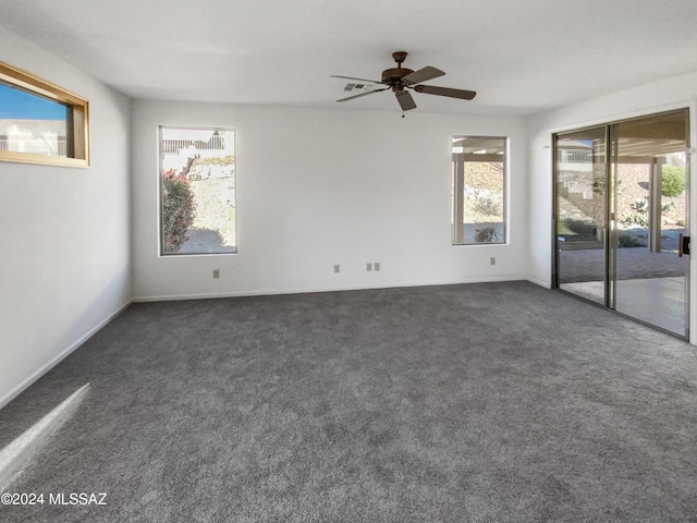 unfurnished room with plenty of natural light, ceiling fan, and dark carpet