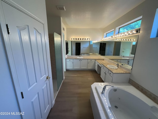 bathroom featuring hardwood / wood-style floors, vanity, and a relaxing tiled tub