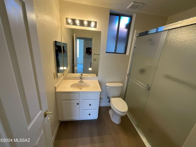 bathroom featuring hardwood / wood-style floors, vanity, an enclosed shower, and toilet