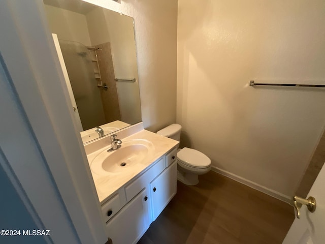 bathroom featuring vanity, toilet, wood-type flooring, and walk in shower