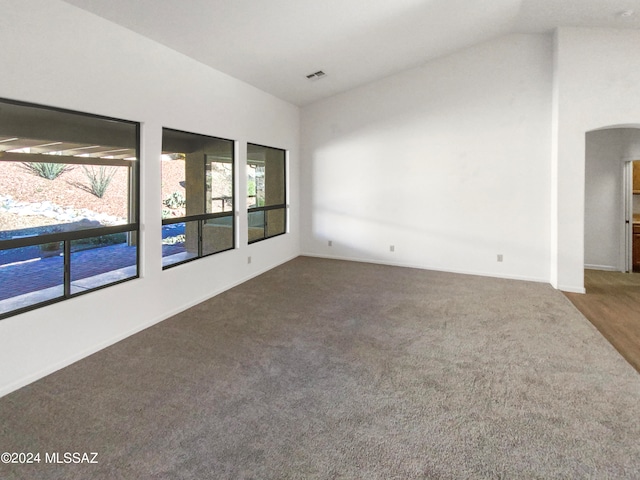 unfurnished room with dark colored carpet and lofted ceiling