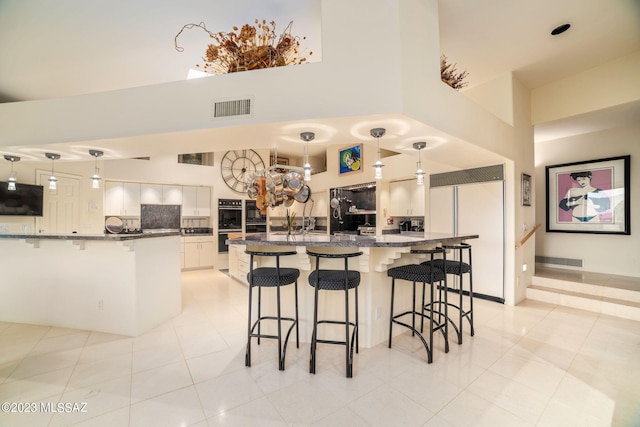 kitchen with decorative light fixtures, decorative backsplash, white cabinetry, and a breakfast bar