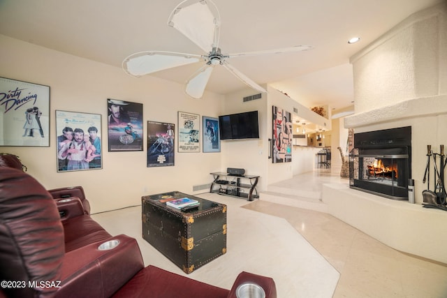 tiled living room featuring ceiling fan and a large fireplace