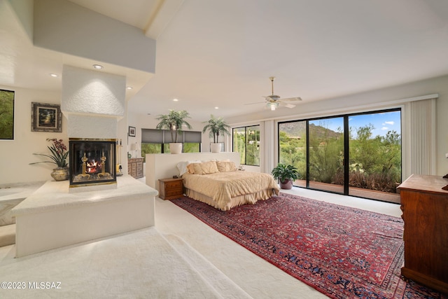 bedroom featuring access to outside, multiple windows, ceiling fan, and a multi sided fireplace