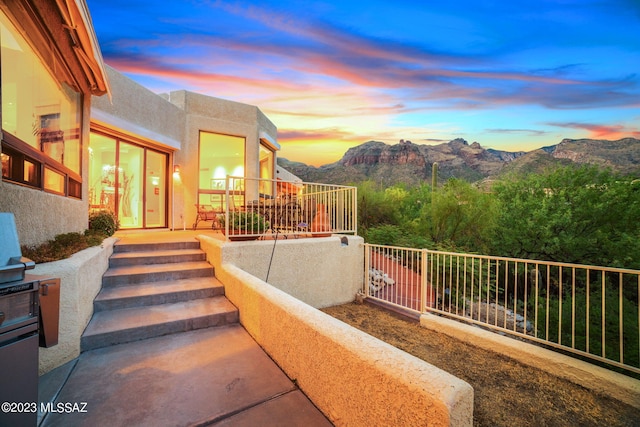 patio terrace at dusk with a mountain view and a balcony