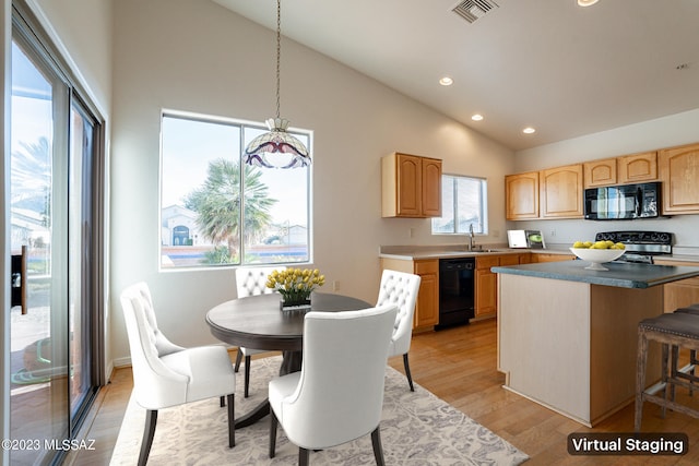 kitchen with hanging light fixtures, a kitchen island, light hardwood / wood-style flooring, high vaulted ceiling, and black appliances