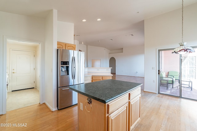 kitchen with stainless steel refrigerator with ice dispenser, light wood-type flooring, and a center island