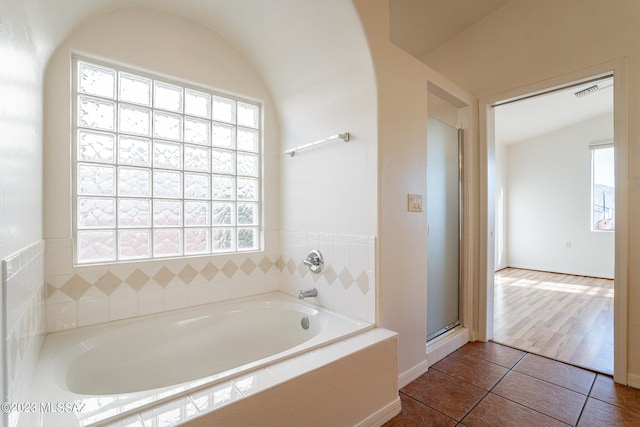 bathroom with shower with separate bathtub, vaulted ceiling, hardwood / wood-style flooring, and a healthy amount of sunlight