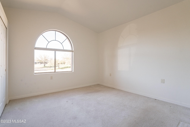 carpeted empty room featuring vaulted ceiling