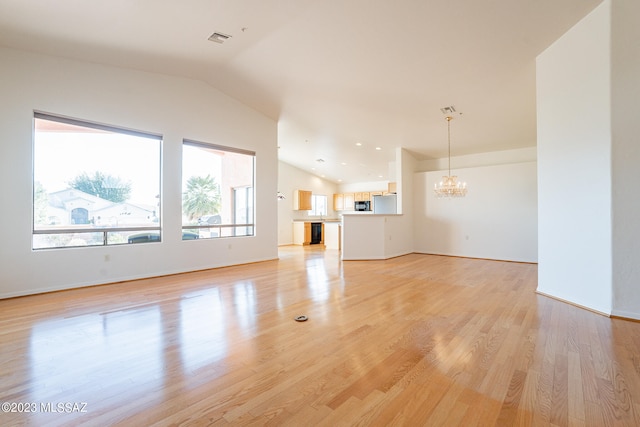 unfurnished living room featuring a chandelier, light hardwood / wood-style floors, and vaulted ceiling