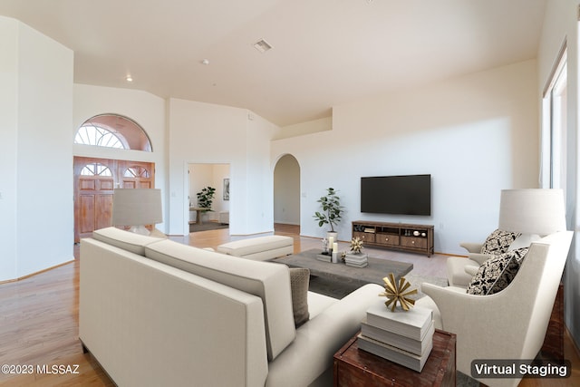 living room featuring light wood-type flooring and a high ceiling