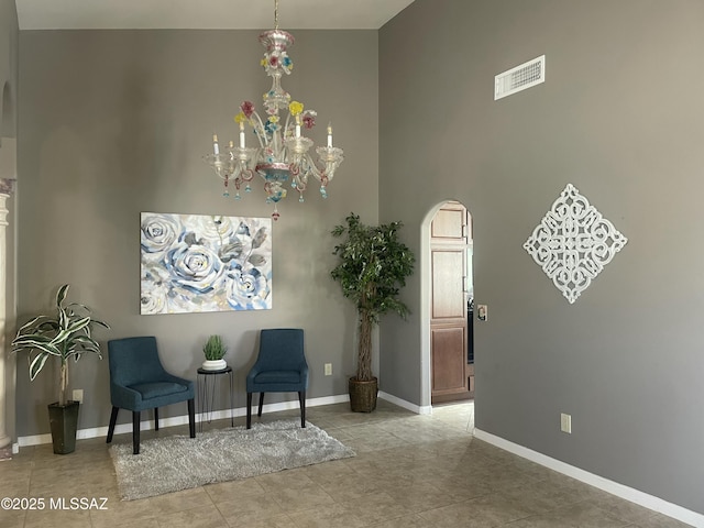 sitting room with visible vents, baseboards, arched walkways, and a high ceiling