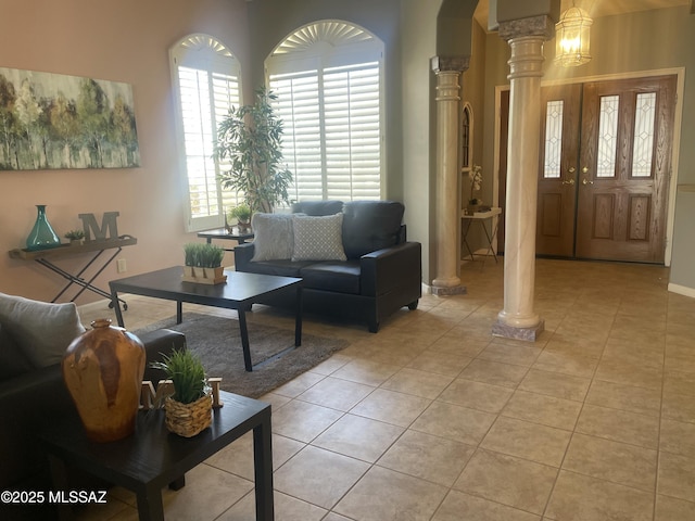 living area with decorative columns, light tile patterned flooring, and arched walkways