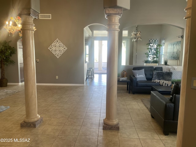 living area with visible vents, ornate columns, baseboards, light tile patterned flooring, and arched walkways