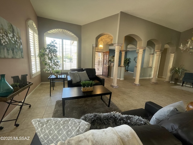 living area featuring decorative columns, light tile patterned flooring, arched walkways, and baseboards