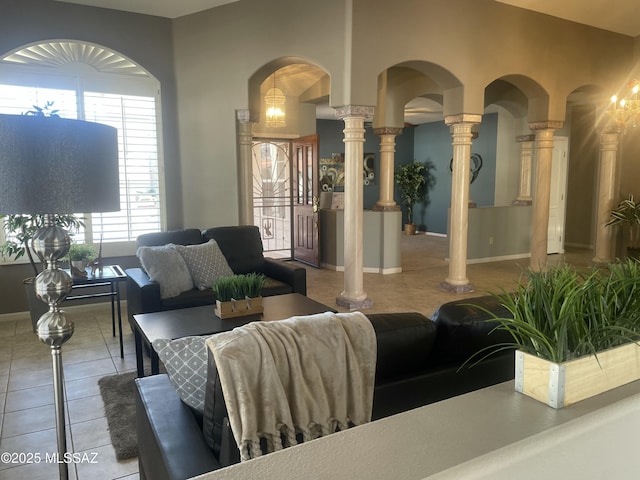 living area with tile patterned flooring, decorative columns, and baseboards