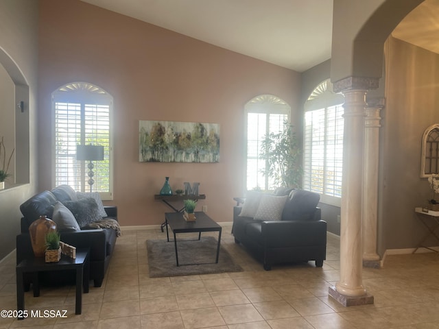 living room featuring lofted ceiling, light tile patterned floors, baseboards, and ornate columns