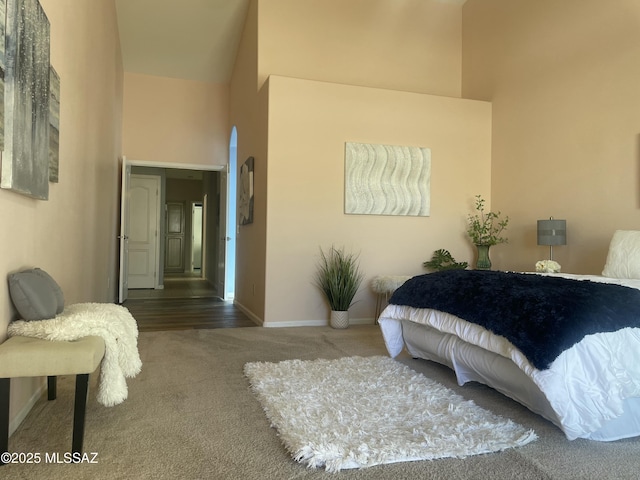 bedroom with baseboards, a high ceiling, and carpet