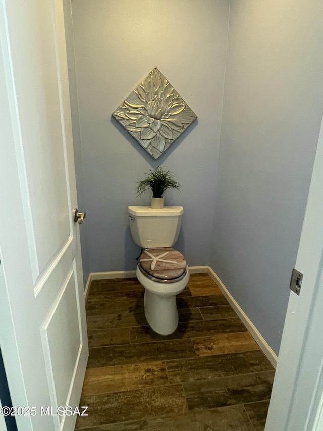 bathroom with baseboards, toilet, and wood finished floors