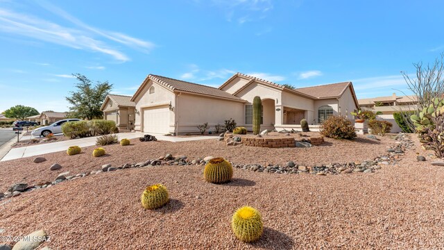 view of side of property featuring stucco siding, driveway, a tile roof, and a garage