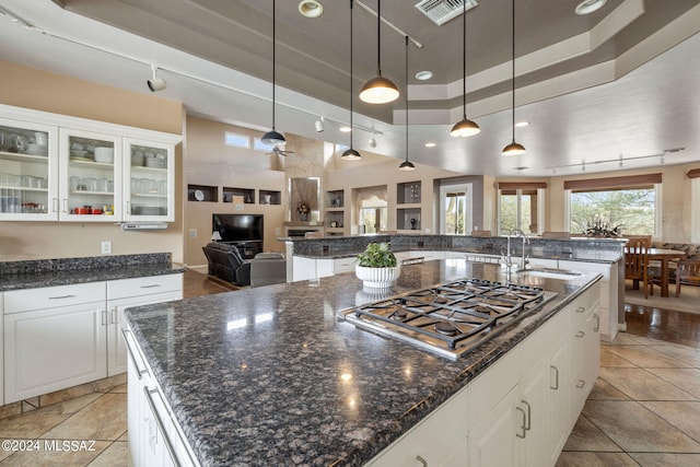 kitchen with an island with sink, white cabinetry, sink, and stainless steel gas cooktop